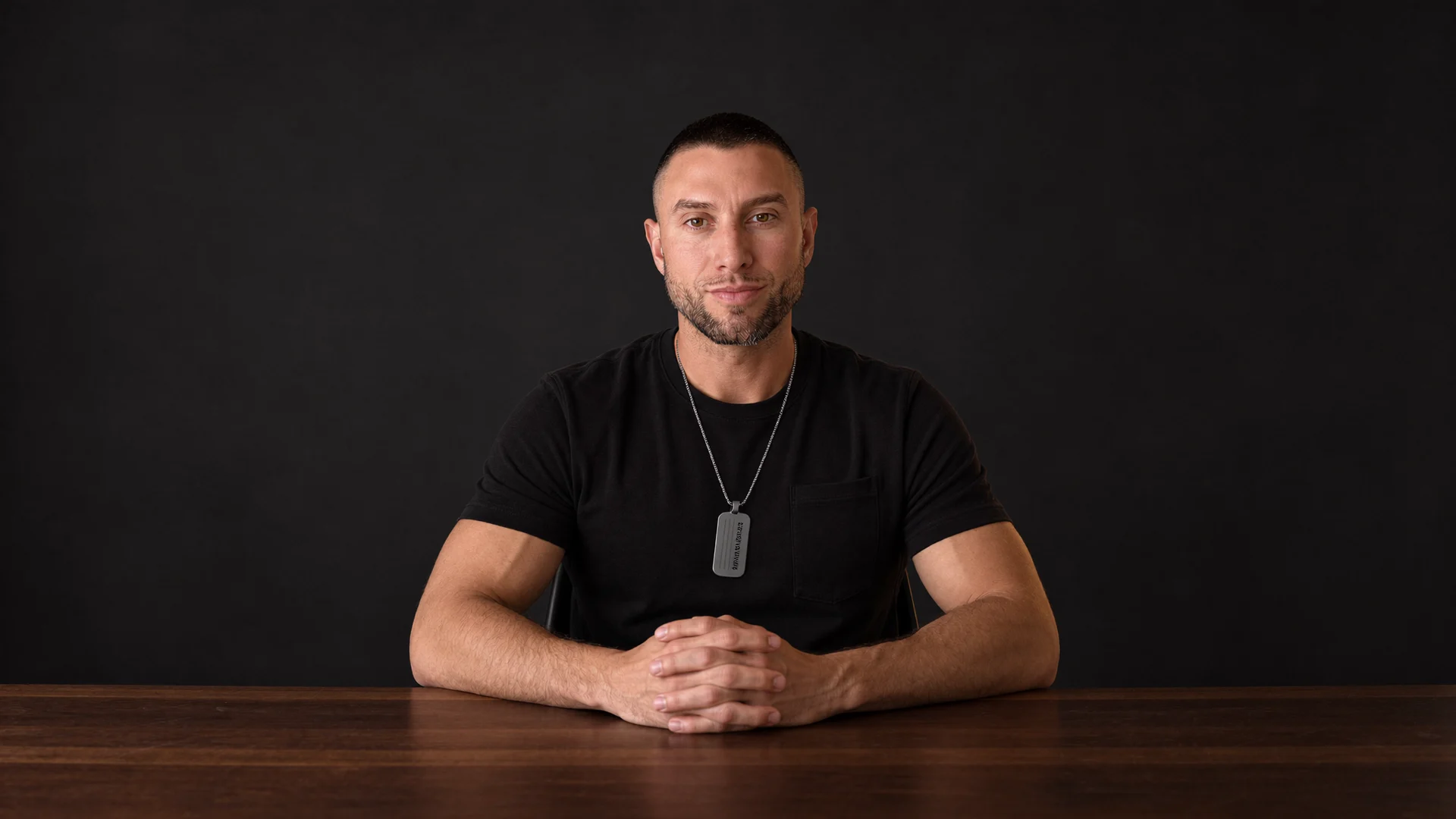 Joey V seated at a dark desk, looking straight at the camera